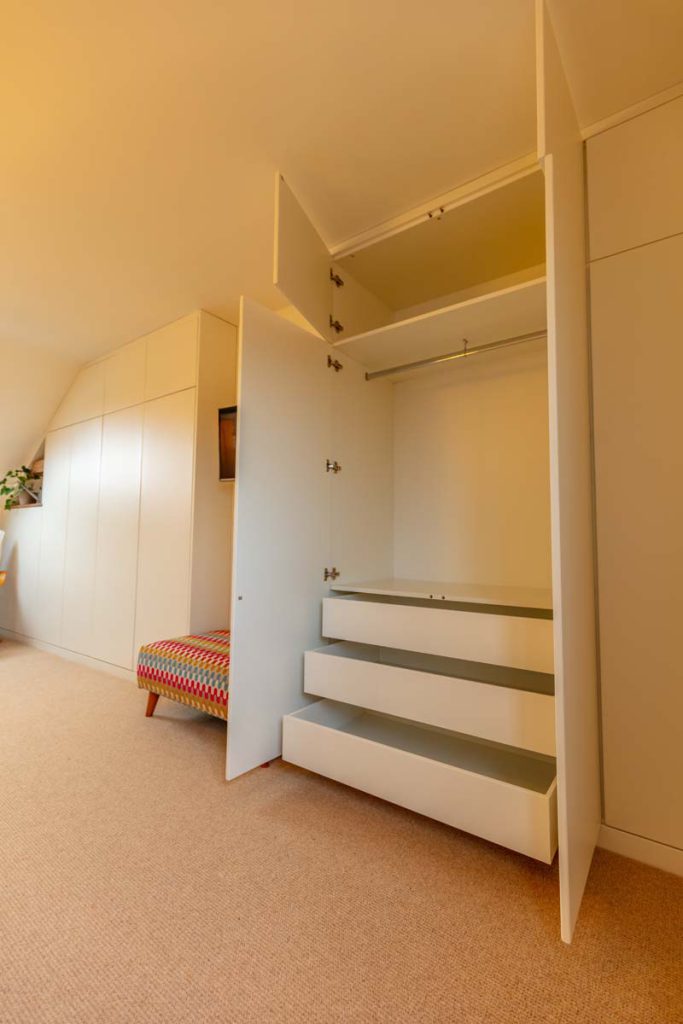 Open fitted wardrobe showing hanging rail, shelves and pull-out drawers in a Horfield dormer loft conversion