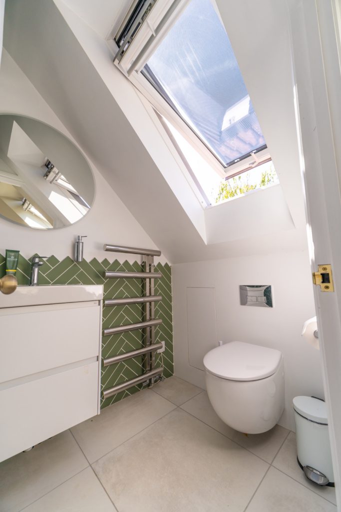En-suite basin, heated towel rail and WC beneath a large skylight in a Redland dormer loft conversion, Bristol