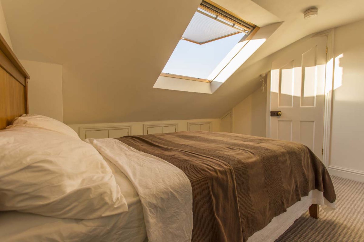 Double bed beneath the sloped ceiling with eaves-storage cupboards in a St Werburgh's dormer loft conversion, Bristol