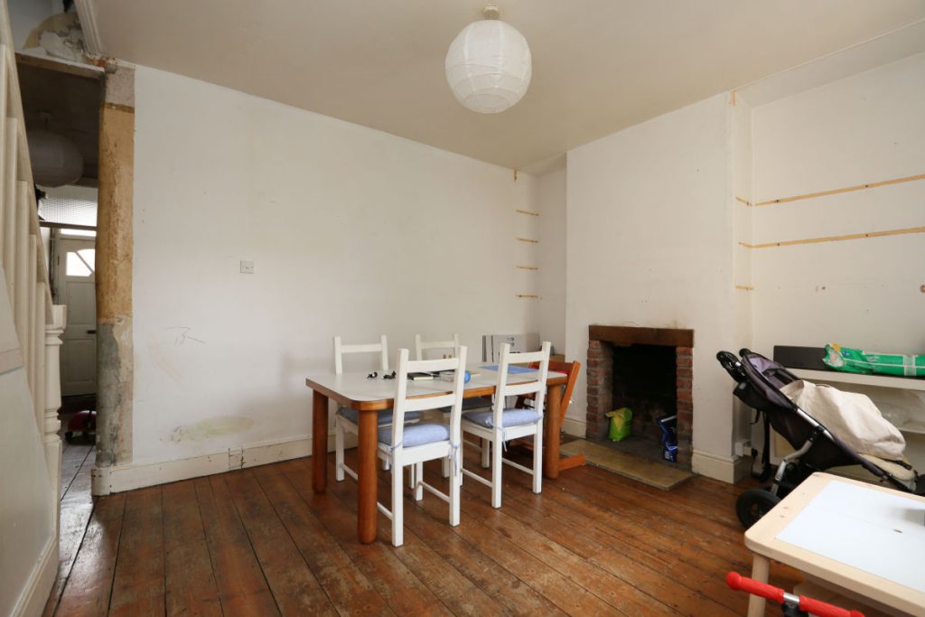 Dining room before refurbishment, with bare plaster and an exposed fireplace, in an Easton terrace, Bristol