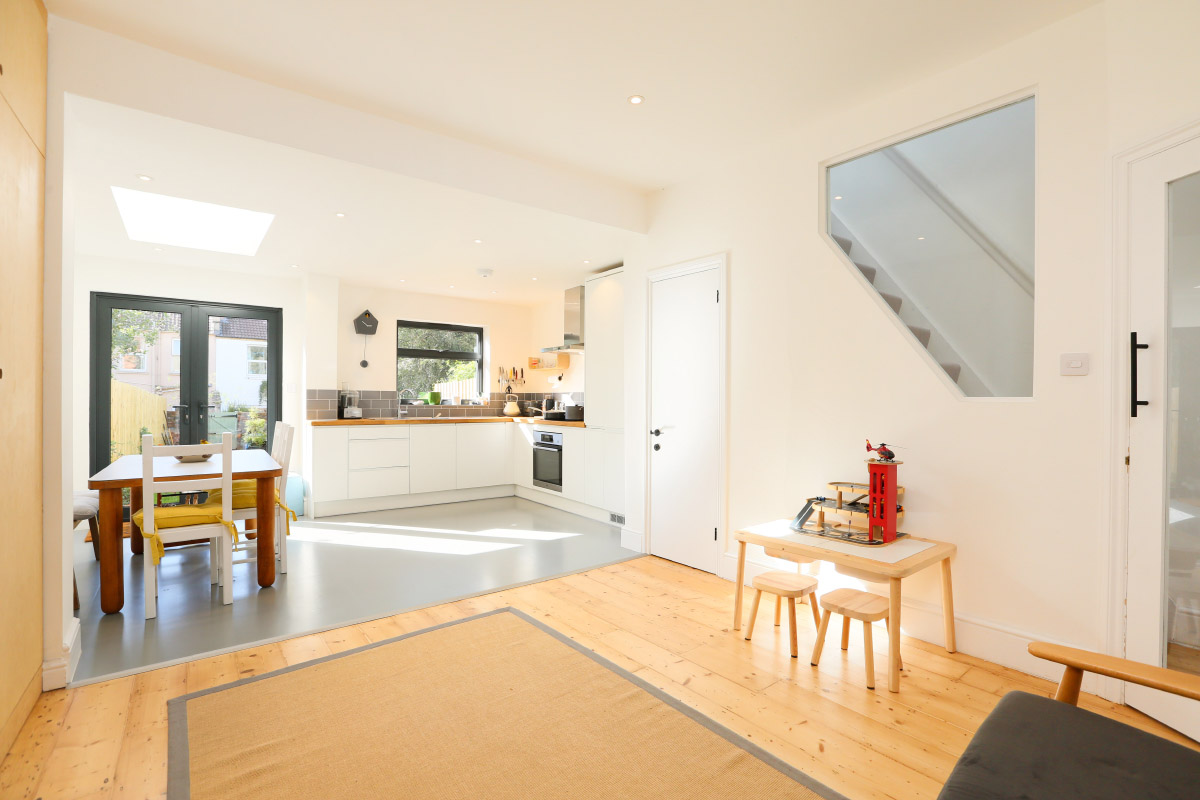 Open-plan living and kitchen with bespoke plywood storage and a glass-panel stairwell after a full house refurbishment in Easton, Bristol