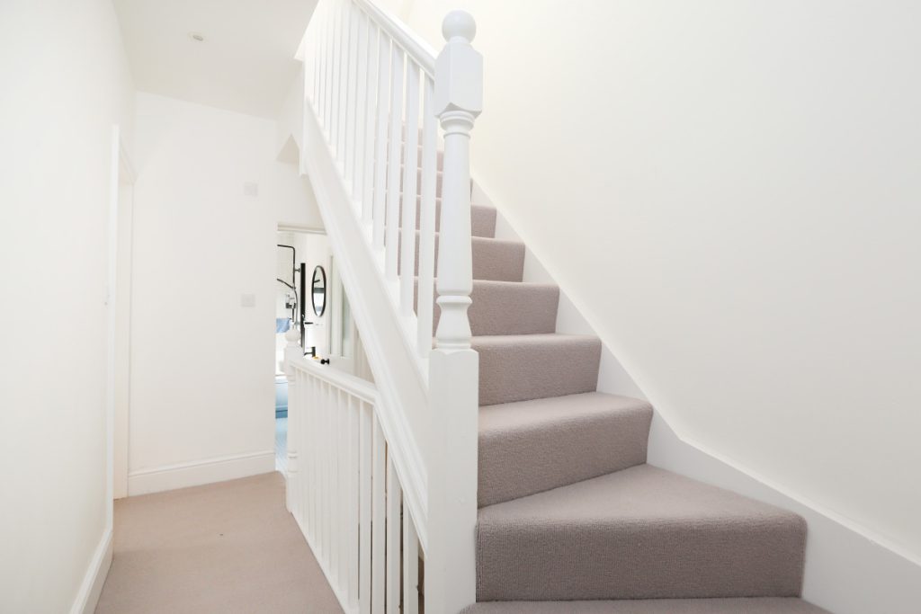 New carpeted staircase with a fire-protected glass-panel stairwell in a full house refurbishment in Easton, Bristol