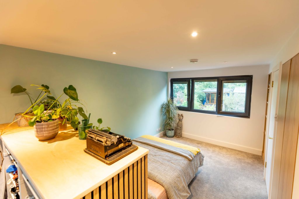 Loft bedroom with sage-green walls, built-in storage and a rooflight in a Bedminster full-width dormer conversion