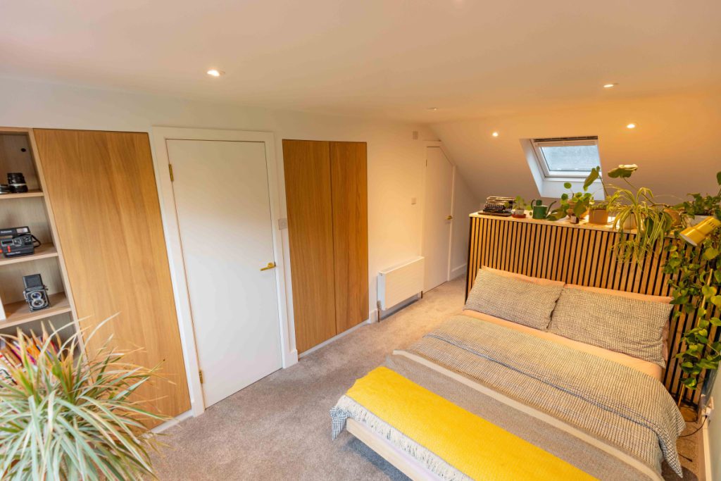 Built-in walk-in wardrobe with oak doors and open shelving in a Bedminster full-width dormer loft conversion
