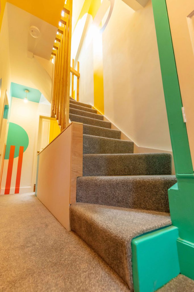 Slatted timber balustrade and colourful geometric mural on the new loft staircase in a Bedminster conversion