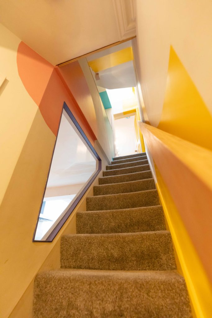 Loft staircase with an angled feature window and colourful painted walls in a Bedminster dormer conversion