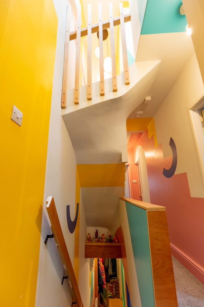 Bright stairwell with bold geometric wall murals and a slatted balustrade in a Bedminster loft conversion