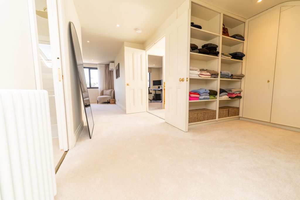 Open walk-in wardrobe with bespoke shelving in a hip-to-gable loft conversion in Bishopston, Bristol