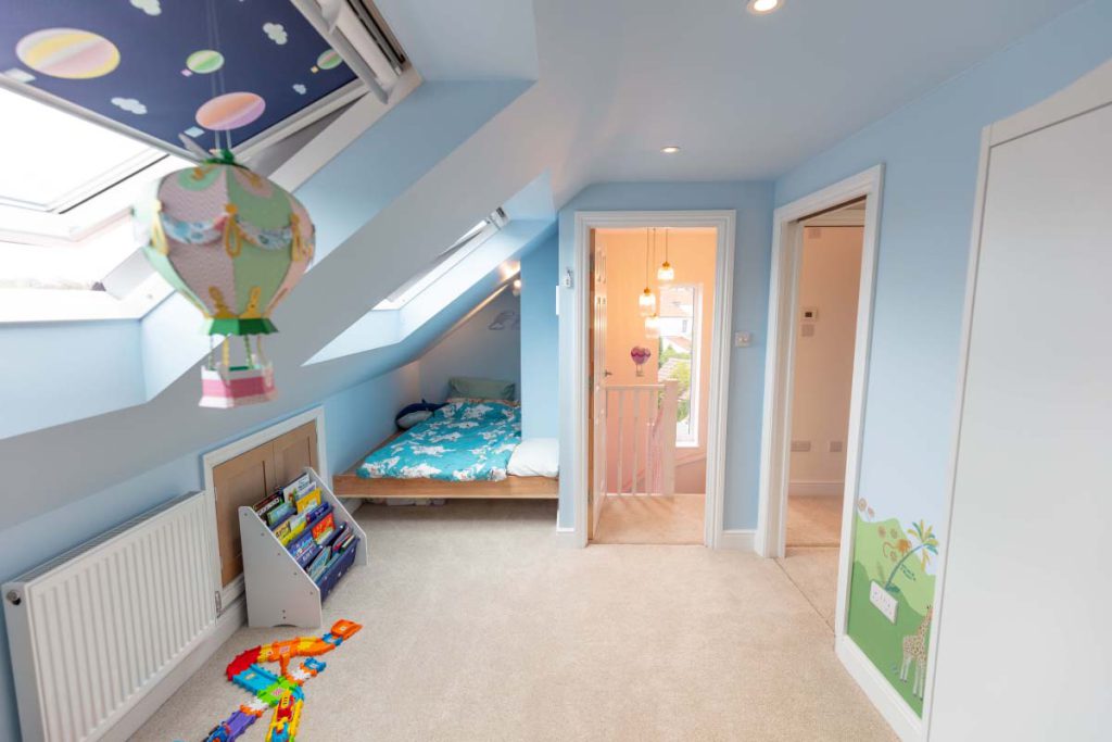 Second loft bedroom in blue with Velux rooflights and a low child's bed in a Brislington hip-to-gable conversion