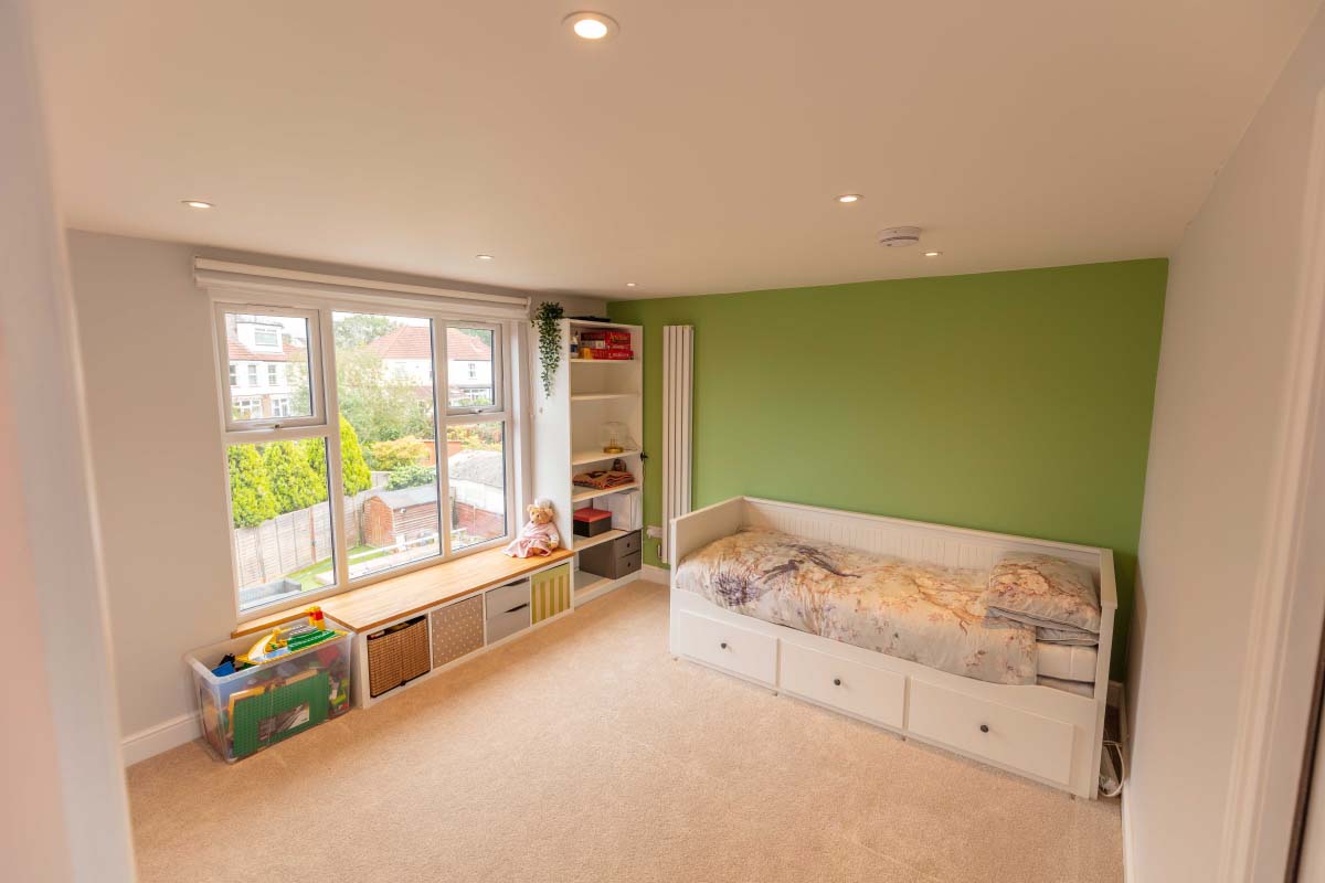 Large loft bedroom with a wide side window and garden view in a hip-to-gable conversion in Brislington, Bristol