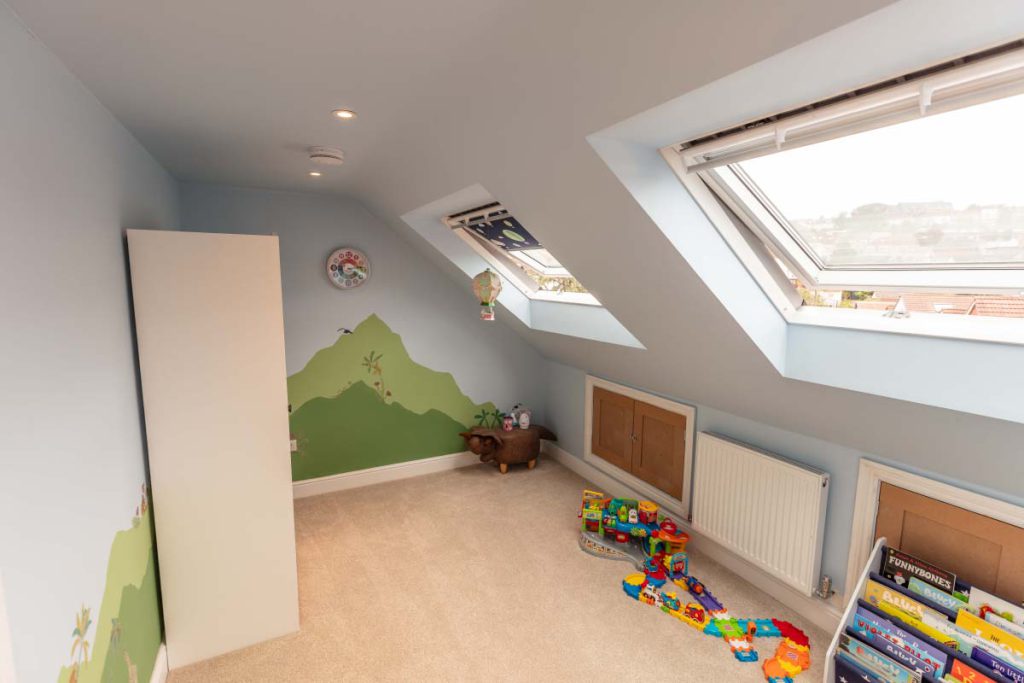 Loft playroom with a mountain wall mural, Velux rooflights and eaves cupboard in a Brislington hip-to-gable conversion