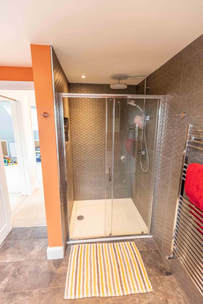Large walk-in shower enclosure with slate floor and heated towel rail in the loft bathroom of a Brislington hip-to-gable conversion