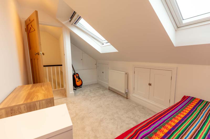 Built-in eaves storage cupboards and rooflights in the guest room of a Knowle hip-to-gable loft conversion