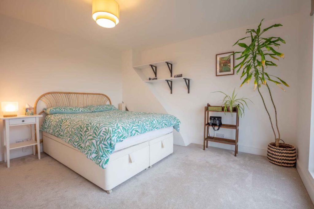 Master bedroom with a double bed and eaves shelving in a hip-to-gable loft conversion in Knowle, Bristol