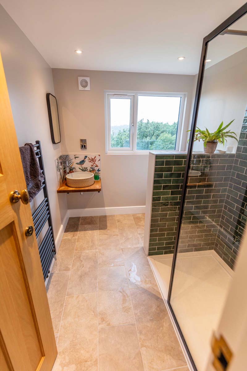 Large shower room with a stone vessel basin, green metro-tiled walk-in shower and valley views in a Knowle hip-to-gable loft conversion