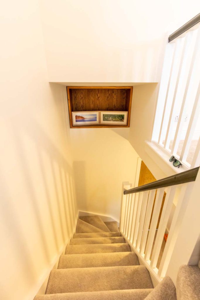 Carpeted staircase with an oak-lined display niche in a Knowle hip-to-gable loft conversion
