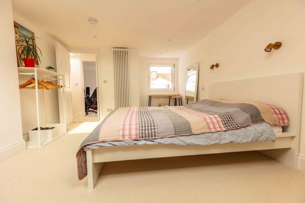 Loft master bedroom with open wardrobe and doorway through to a study in a Bedminster dormer conversion