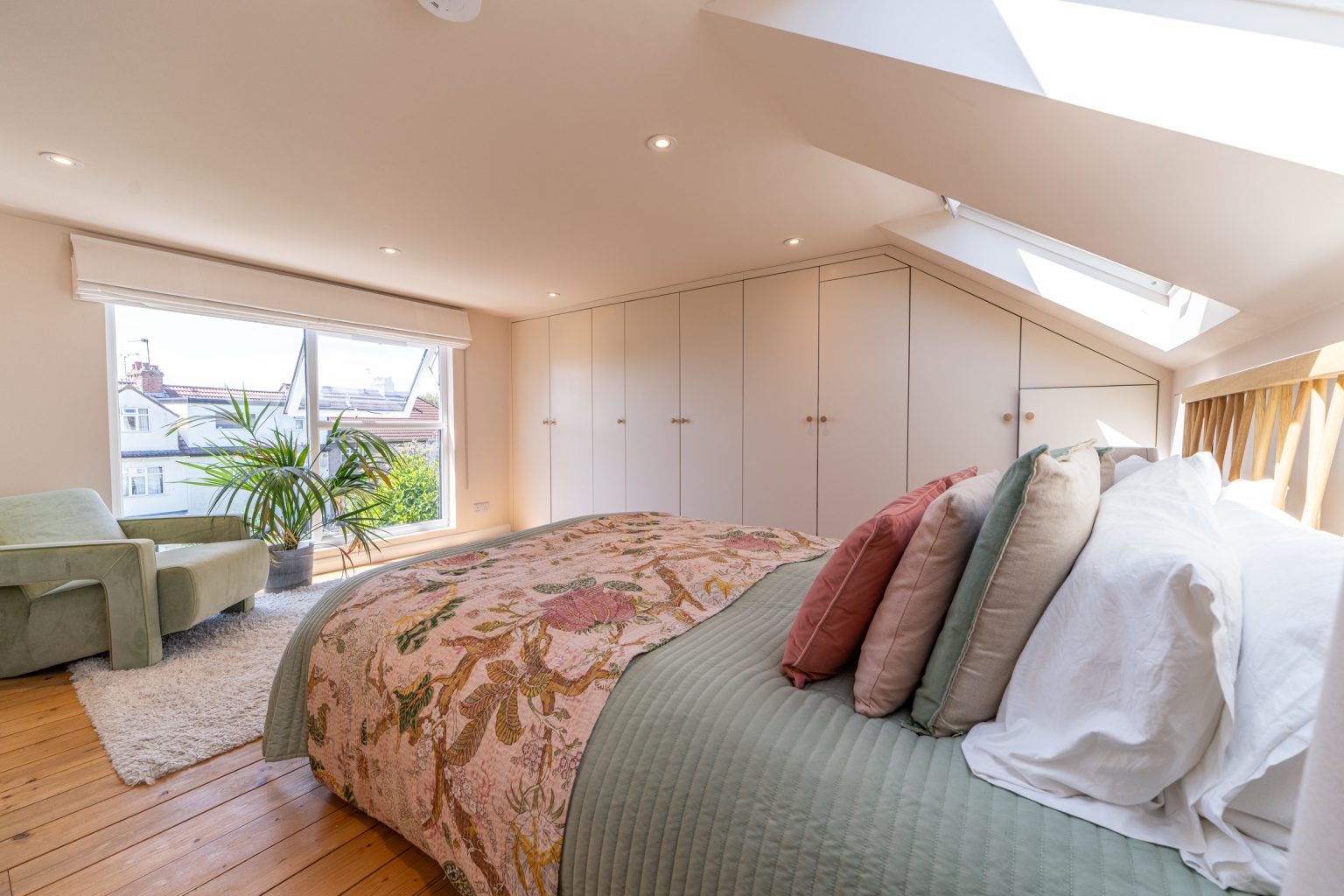 Loft bedroom with a wall of built-in wardrobes and a natural wood floor in a low-ceiling dormer conversion in Horfield, Bristol
