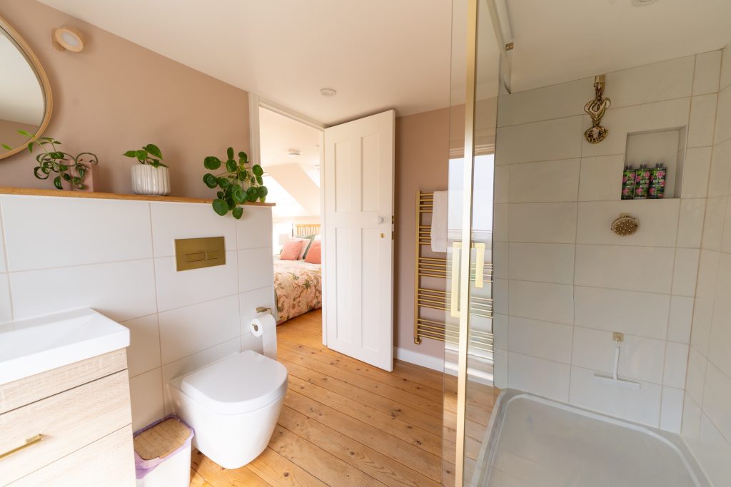 En-suite shower room with brass fittings and natural wood floors in a low-ceiling dormer loft conversion in Horfield, Bristol