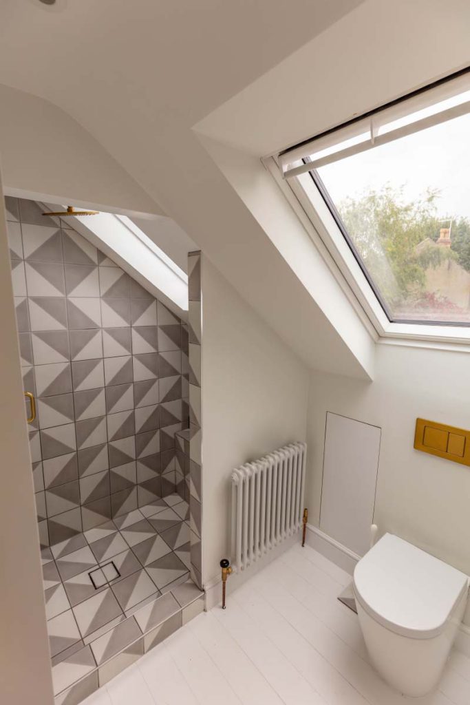 En-suite shower room with geometric grey tiles and a skylight in a Montpellier loft conversion